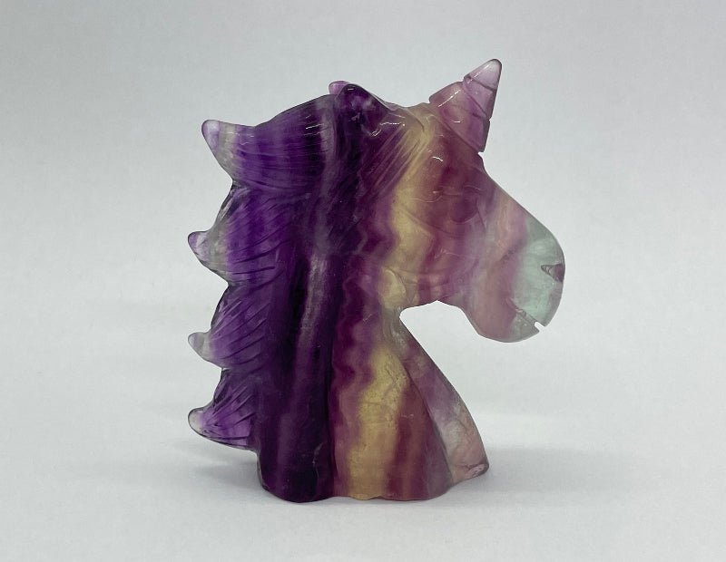 Glänzendes Einhorn aus Regenbogen-Fluorit, farbenprächtige Kristallstruktur.