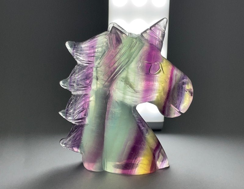 Poliertes Kristall-Einhorn aus Regenbogen-Fluorit mit schillernden Farben, kunstvoll geschnitzt.