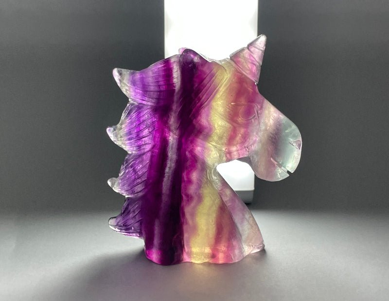 Handgeschnitztes Regenbogen-Fluorit Einhorn in kräftigen Grün- und Violetttönen
